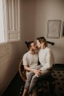 Glückliches Paar, das im Sessel sitzt und sich beim Binden zu Hause anschaut — Stockfoto
