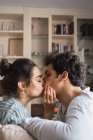 Giovane uomo e donna seduti sul divano in soggiorno e baciare — Foto stock