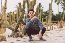 Young man sitting at cactus — Stock Photo