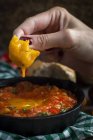 Menschenhand über Spiegelei mit Tomate, Paprika und Brot in der Pfanne — Stockfoto