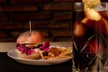 Вкусный бургер с картошкой фри на тарелке и стаканом кокаина — стоковое фото