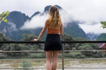 Mulher inclinada em corrimãos olhando para as montanhas — Fotografia de Stock
