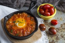 Смажене яйце з помідорами на сковороді на дерев'яній дошці — стокове фото