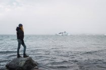 Chica de pie en la roca en el mar - foto de stock