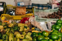 Small plush bear toy placed in boxes with different fruits on market. — Stock Photo