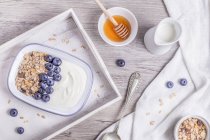 Oats and blueberry with honey breakfast top view over wooden tray on table — Stock Photo