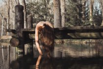 Femme nue couchée et touchant l'eau — Photo de stock