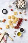 Ravioli crudi e spezie con pomodori e funghi in tavola — Foto stock