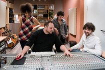 Sound directors sitting at audio mixer board while working in modern recording studio — Stock Photo