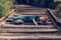 Dreckiger Junge schläft auf Eisenbahn — Stockfoto