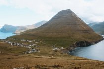Vista al pequeño pueblo en la gran montaña verde en las Islas Feroe - foto de stock