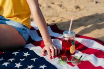 Crop girl with drink on American flag — Stock Photo