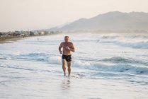 Le vieil homme fort fait de l'exercice sur la plage — Photo de stock