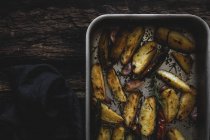 Cales de pommes de terre croustillantes dorées rôties dans une plaque à pâtisserie sur une table en bois — Photo de stock