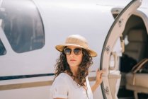 Красивая женщина в солнечных очках и шляпе рядом с самолетом. — стоковое фото