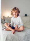 Netter lächelnder Junge sitzt mit digitalem Tablet auf Sofa — Stockfoto