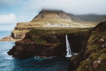 Мальовничий вид з прибережних скель і обприскування водоспад на Feroe острови — стокове фото