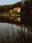 Casa grande com telhado laranja construído na floresta e lagoa em Feroe Island — Fotografia de Stock