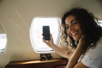 Femme prenant une photo à travers la fenêtre de l'avion — Photo de stock