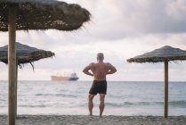 Viejo fuerte hace ejercicio en la playa - foto de stock