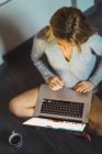 Jovem mulher em suéter digitando no laptop — Fotografia de Stock