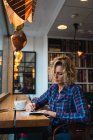 Жінка сидить у кафе і пише в блокноті — стокове фото