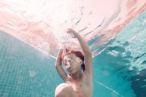 Junge taucht in transparentes blaues Poolwasser — Stockfoto