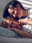 Schöne Frau liegt auf Bett hinter süßem Jungen und berührt seine Wange vorsichtig — Stockfoto