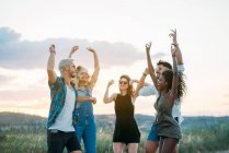 Gruppe junger Leute in lässigen Outfits lachen und tanzen, während sie gemeinsam Spaß in der schönen Landschaft haben — Stockfoto