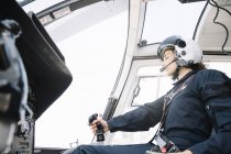 Piloto focado fêmea sentado e operando em helicóptero — Fotografia de Stock