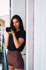 Jovem mulher pensativa em pé na varanda com câmera de fotos — Fotografia de Stock