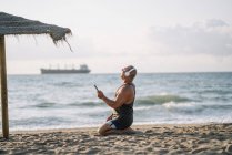 Літній чоловік слухає музику на пляжі — стокове фото