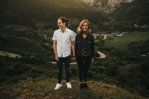 Man and woman looking away while standing on background of amazing mountains and valley together — Stock Photo