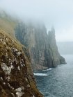 Oceano e scogliera rocciosa tra le nuvole sull'isola di Feroe — Foto stock