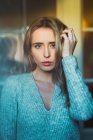 Portrait of young pensive woman in sweater posing at home — Stock Photo
