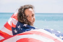 Девушка позирует на пляже с флагом США. — стоковое фото