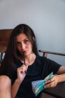 Giovane donna bruna seduta in camera con piccolo notebook e matita — Foto stock