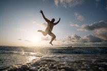 Silhouette eines Mannes, der am Strand springt — Stockfoto