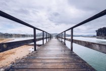 Verwitterter Umberpier am Ufer nahe der Oberfläche ruhigen Wassers an bewölkten Tagen in Asturien, Spanien — Stockfoto