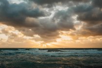 Bright sun setting over waving sea behind thick clouds in Miami — Stock Photo