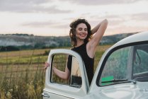 Женщина опирается на винтажный автомобиль в сельской местности — стоковое фото