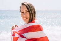 Ein Mädchen posiert am Strand mit der Flagge der USA. — Stockfoto