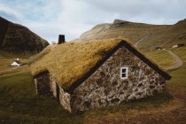 Casa rurale in pietra con erba sul tetto in collina sulle isole Feroe — Foto stock