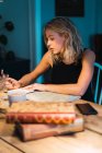 Блондинка, сидящая за столом с книгами, картой, кофе и планированием путешествия — стоковое фото