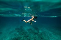 Anonymous boy snorkeling in dark sea water — Stock Photo