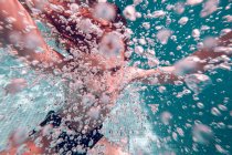 Enfant plongeant dans l'eau avec des bulles d'air sur fond d'eau transparente — Photo de stock