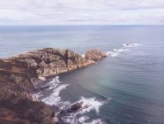 Vista incrível da água do mar salpicando perto de longo penhasco rochoso em dia nublado em Astúrias, Espanha — Fotografia de Stock