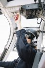 Pilota donna concentrata in casco seduto e operante in elicottero — Foto stock
