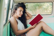 Mulher sentada dentro da caravana e livro de leitura — Fotografia de Stock