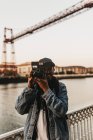 Cheerful man with camera on embankment — Stock Photo